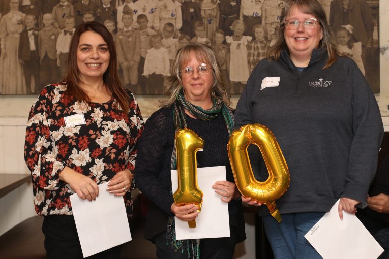 Staff holding 10 years of service balloons.