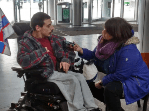 Person in wheelchair having a conversation with a lady in a blue jacket.
