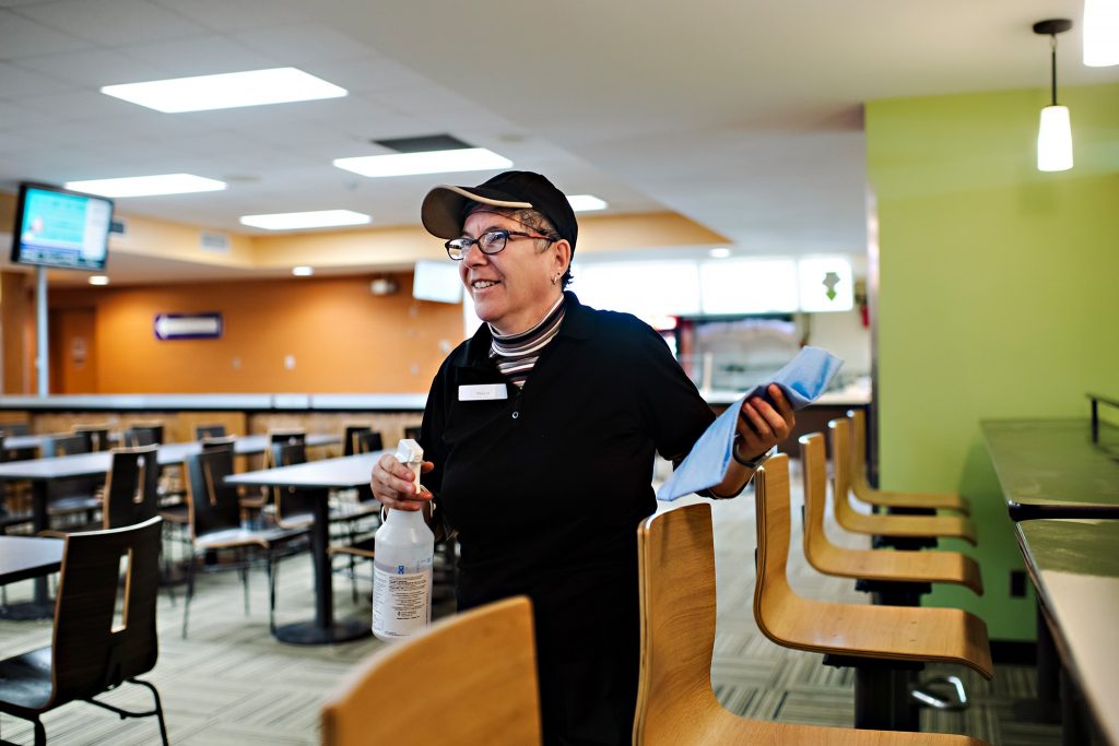 Person supported by KW Career Compass smiling while cleaning at the Union Market.