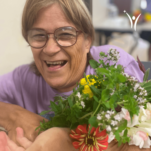 Woman smiling while holding a bouquet of flowers.