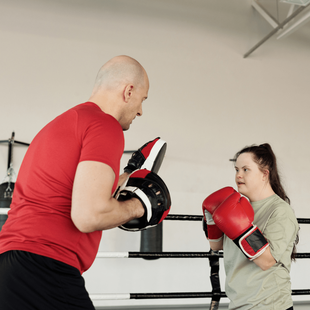 A person practicing boxing with their coach.