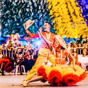 Two people dancing at a Carnival with very bright coloured clothes