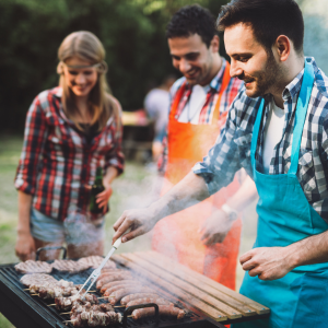 A group of people gathered around a barbecue cooking some food.