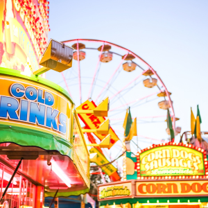 A drinks stand, corn dog stand and a ferris wheel at a carnival