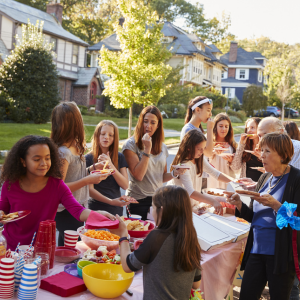 Neighbours gathering at a table of picnic food
