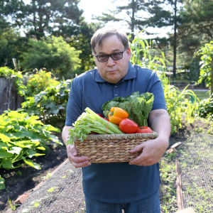 A person holding a basket of fresh vegetables that they have harvested