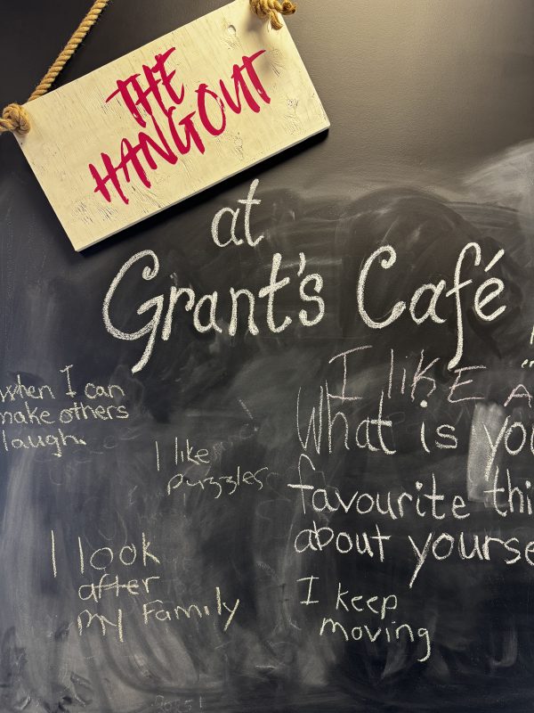 chalk board wall that has a sign "THE HANGOUT" at Grants Cafe and a bunch of writing on the board.