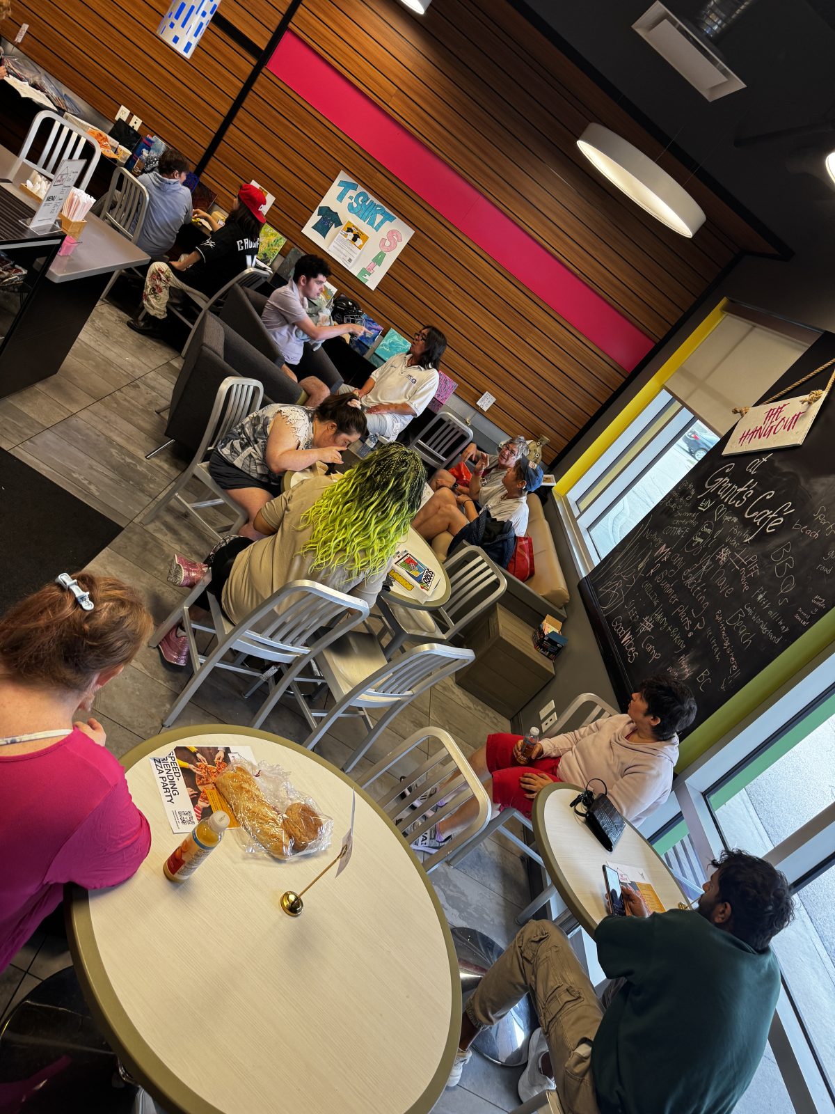 an overhead view of the Hangout at Grants Cafe. It's busy with people sitting at all the tables and couch and chairs. People are playing games, drinking coffee and connecting.