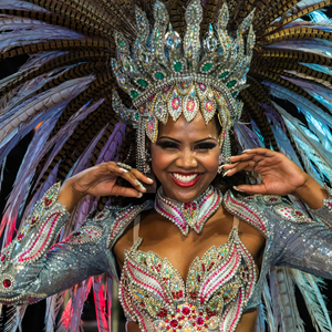 A woman wearing a beautiful and elaborate costume with a headdress and beads of feathers and a bodice of beads.