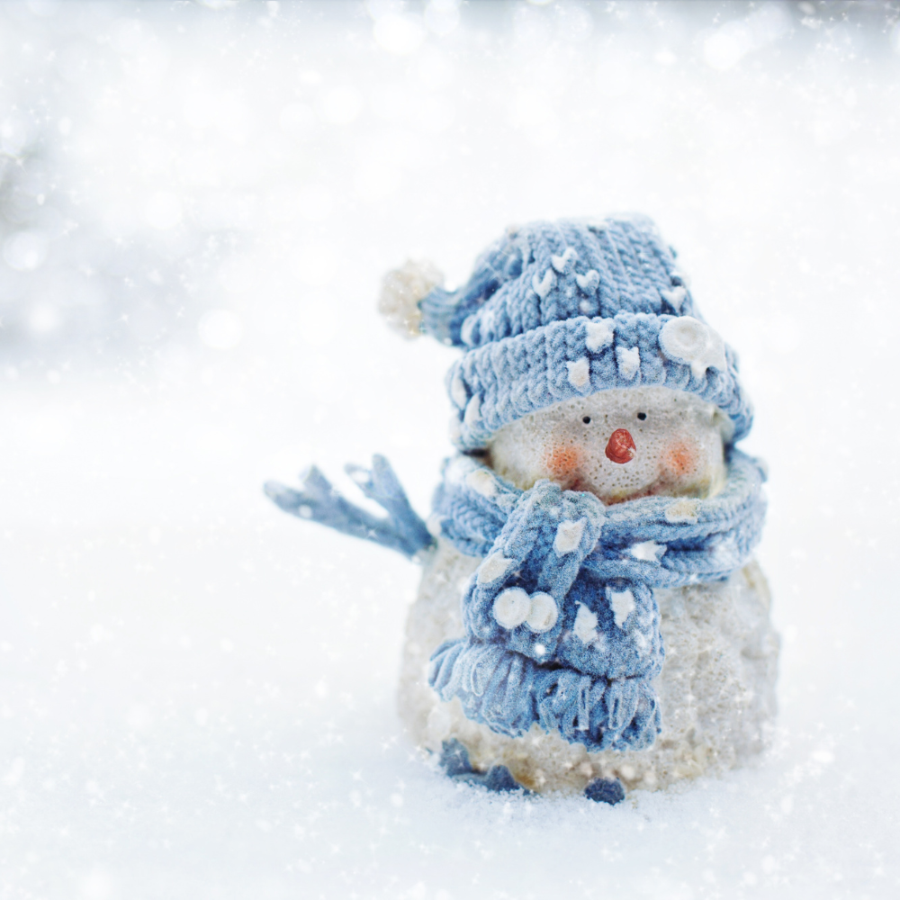 A snowman dressed in a blue hat and scarf.
