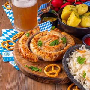 A display of german sausage, beer, sauerkraut and pretzels.