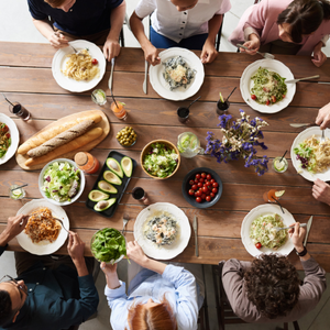 A top down view of a table full of food with a group of people sitting around it sharing a meal.