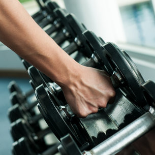 A row of dumbbell weights. A person's hand grabbing one of the weights. 