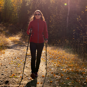 A warmly dressed person walking on a trail through the fall leaves.