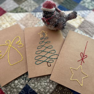 Three cards with holiday themed embroidery on them.