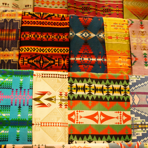 a display of colourful blankets hand made by native americans with traditional designs