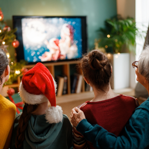 A group of people watching a movie. One is wearing a Santa hat.