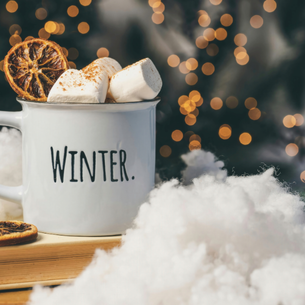 A mug of hot cocoa with marshmallows overflowing. The mug says "Winter" on it.