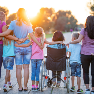 A lineup of people with their backs to the viewpoint. Their arms are around each other. The people range from children to adults and includes a person using a wheelchair.