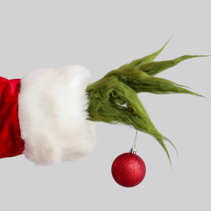 A furry green hand holding a red tree ornament. 