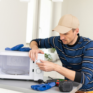 A person making repairs to a microwave