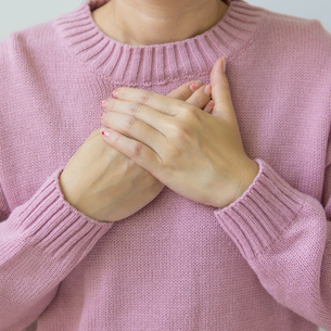 A person holding their hands on their heart in a calm and relaxed way.