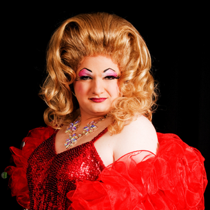 A drag queen wearing red with a black background