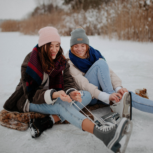 two people lacing up their ice skates together
