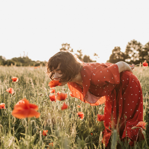 A person bending over to smell some spring flowers.