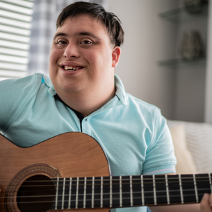 A person holding a guitar and smiling.