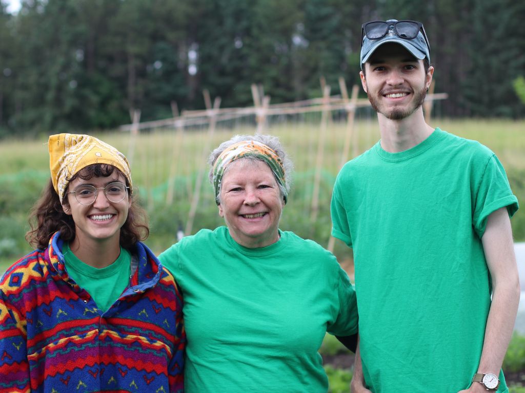 three people smiling standing in a field
