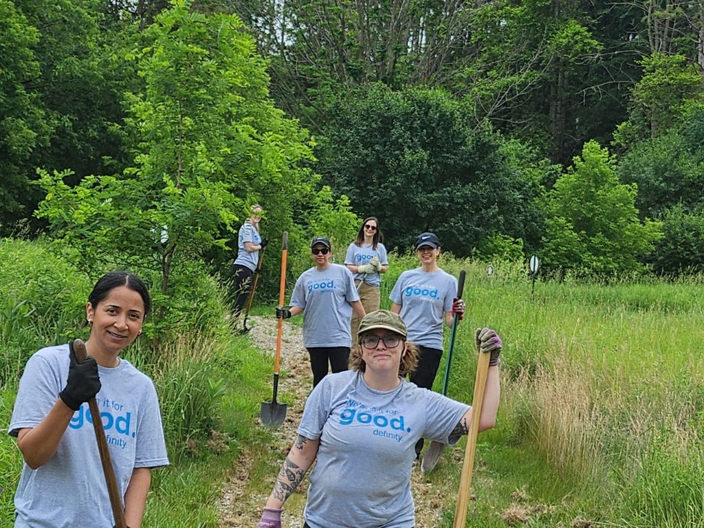 a group of people holding farming equipment on a trail