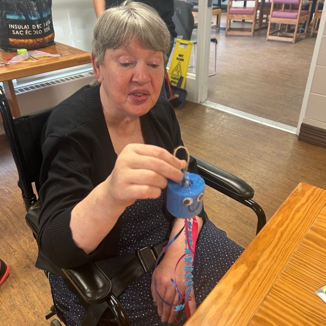 older woman holding up a jellyfish craft