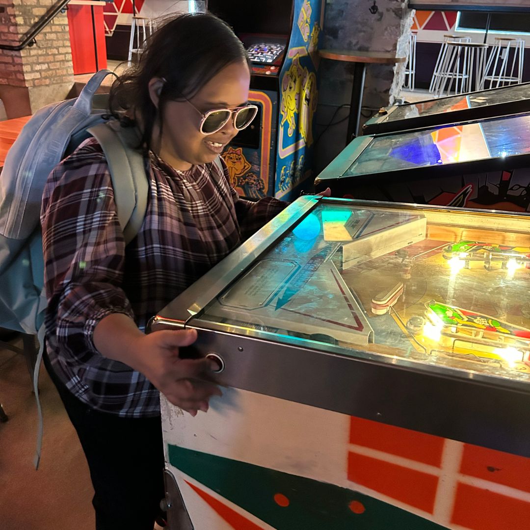 woman with sunglasses son playing pinball. she is an icon