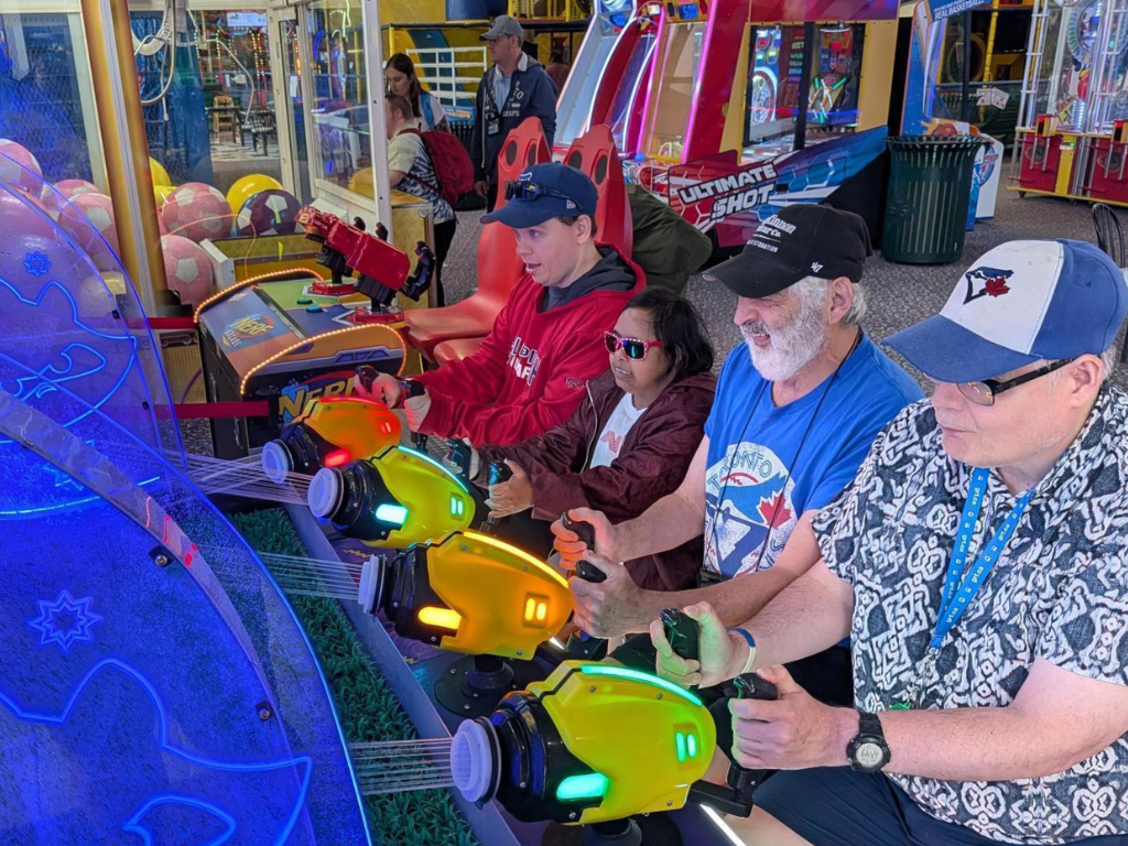 group of four people playing a water arcade game together
